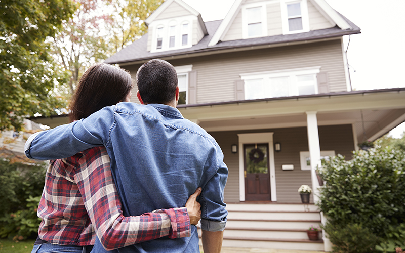 Rear View Of Loving Couple Looking At House